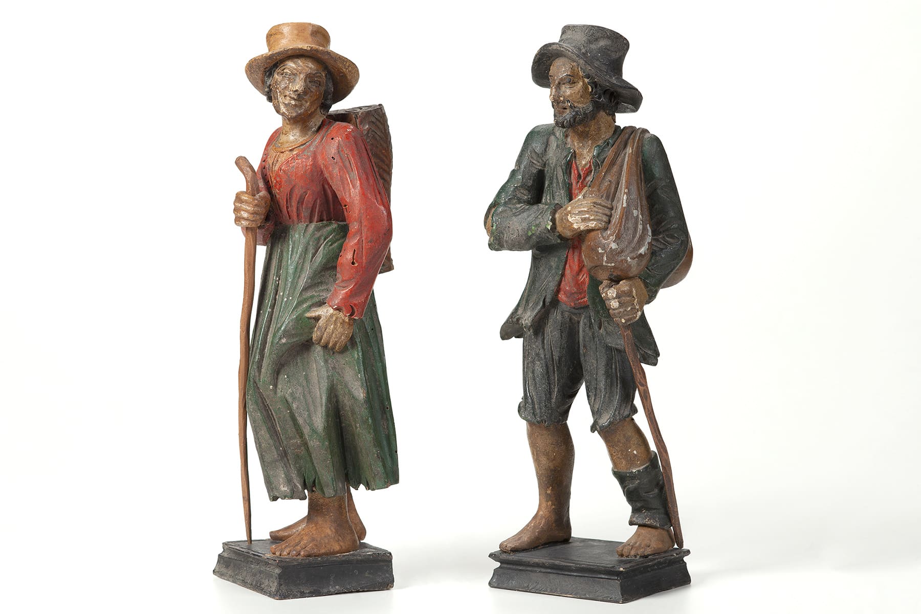 Eine Bettlerin und ein Bettler, beide barfuß, mit Hut und Gehstock
